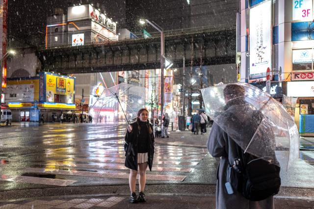 Pedestrians hold umbrellas as it snows and rains in Tokyo's Akihabara district on January 2, 2026. (Photo by Philip FONG / AFP)