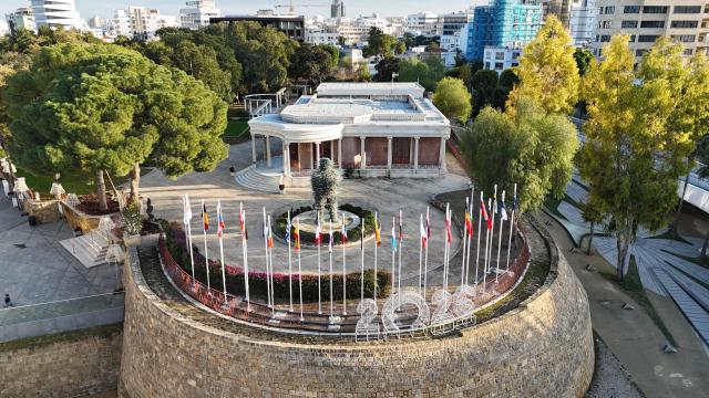This aerial picture shows flags of EU member states adorning a section of the Venetian Walls of the divided capital Nicosia, on the grounds of the old municipal palace at Eleftheria Square on January 2, 2026. The Republic of Cyprus will hold the Presidency of the Council of the European Union for the first half of 2026. (Photo by Etienne TORBEY / AFP)