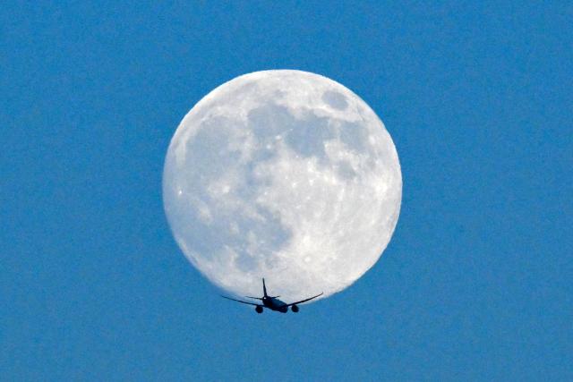A jet flies past the January full moon, also known as "Wolf Moon", over Frankfurt am Main, western Germany on January 2, 2026. (Photo by Kirill KUDRYAVTSEV / AFP)