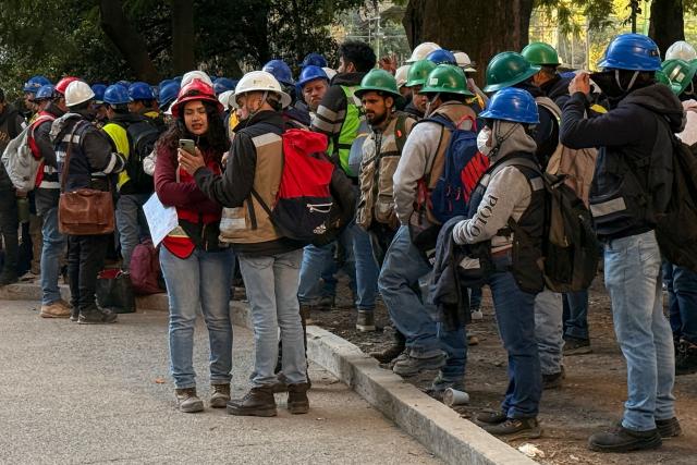 Workers of a construction site use their mobile phones on the street after they evacuated the site during a 6.5 magnitude earthquake in Mexico City, on January 2, 2026. A 6.5-magnitude earthquake shook Mexico City and parts of southwestern Guerrero state on Friday, the national seismological service confirmed. (Photo by David GANNON / AFP)