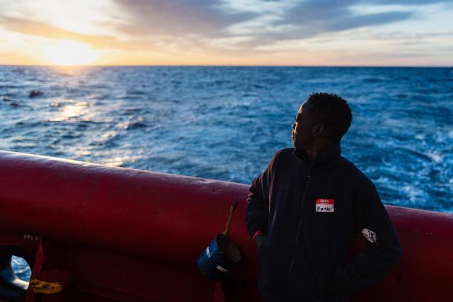A young man looks onboard the rescue ship "Ocean Viking" operated by humanitarian NGO SOS Mediterranee as the sun rises, in the Mediterranean Sea near the Italian coast on January 2, 2026. 33 migrants were rescued by crew members of the migrants rescue ship "Ocean Viking" operated by the NGO SOS Mediterranee. They had been stranded on the oil tanker the 'Maridive 703' since their initial rescue 5 days ago in the joint search zone between Malta and Tunisia in international Mediterranean waters. (Photo by Sameer Al-DOUMY / AFP)