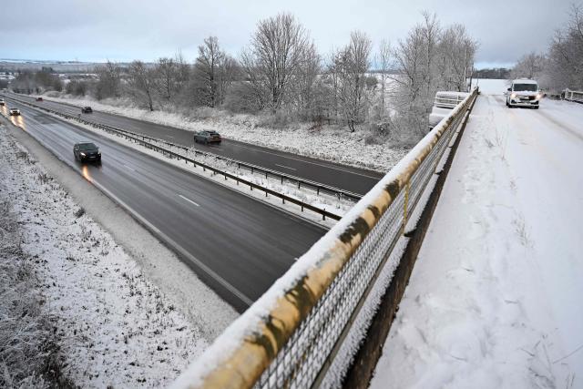 Vehicles move along a carriageway of the A30 motorway as another vehicle drives across a bridge at Fontoy, north-eastern France on January 2, 2026, after heavy snowfall struck the region. (Photo by Jean-Christophe VERHAEGEN / AFP)