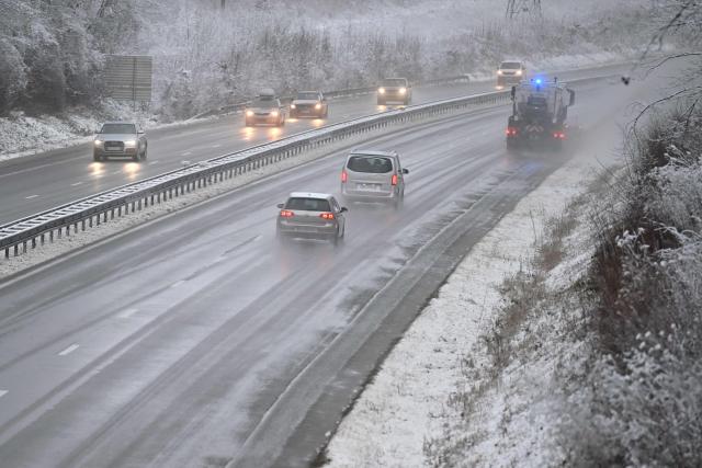 Vehicles move along a carriageway of the A30 motorway as they pass a snowplough at Fontoy, north-eastern France on January 2, 2026, after heavy snowfall struck the region. (Photo by Jean-Christophe VERHAEGEN / AFP)