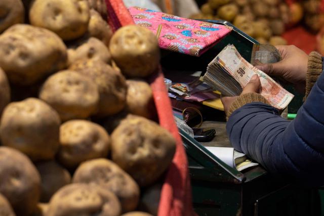 (FILES) A potato saleswoman counts bills product of her sales in Lima's Santa Anita Market during the morning sale session on September 21, 2022. Peru registered 1.51% inflation in 2025, within the range forecast by the Central Bank and the lowest in the last eight years, the state-run National Institute of Statistics and Informatics (INEI) reported on January 2, 2026. (Photo by Cris BOURONCLE / AFP)