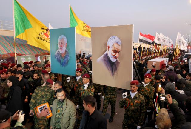 Mourners from Iraq's Popular Mobilization Forces carry portraits of slain commander of Iran's Revolutionary Guards Qasem Soleimani (R) and Iraqi commander Abu Mahdi al-Muhandis (L) during a ceremony at Baghdad's International Airport Road on January 2, 2026, to commemorate the fifth anniversary of their killing in a US drone strike. (Photo by AHMAD AL-RUBAYE / AFP)