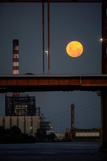 The first moon of the year, the "Wolf Moon," is seen rising through a bridge in the La Boca neighborhood in Buenos Aires on January 2, 2026. (Photo by TOMAS CUESTA / AFP)