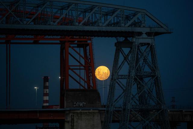 TOPSHOT - The first moon of the year, the "Wolf Moon," is seen rising through a bridge in the La Boca neighborhood in Buenos Aires on January 2, 2026. (Photo by TOMAS CUESTA / AFP)