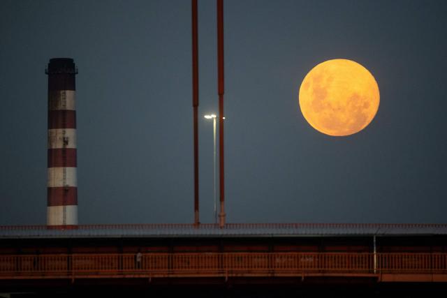 The first moon of the year, the "Wolf Moon," is seen rising through a bridge in the La Boca neighborhood in Buenos Aires on January 2, 2026. (Photo by TOMAS CUESTA / AFP)