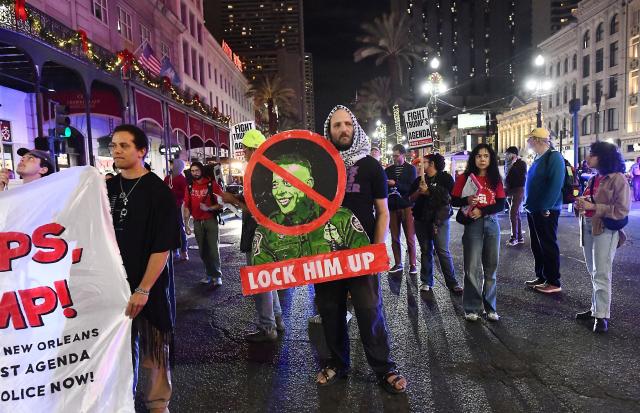 A protester holds an image of Gregory Bovino, chief patrol agent with the US Border Patrol, reading "Lock Him Up" during a "No Trump, No Troops" rally against Trump’s immigration policies and Louisiana Governor Jeff Landry’s National Guard deployment in New Orleans, January 2, 2026. (Photo by Octavio JONES / AFP)