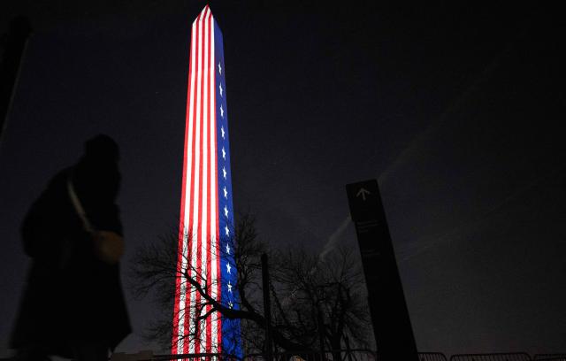 People walk toward the Washington Monument as the US national flag is projected onto it during the "Illumination of America" event marking America’s 250th anniversary at the National Mall in Washington, DC, on January 2, 2026. (Photo by ANDREW CABALLERO-REYNOLDS / AFP)