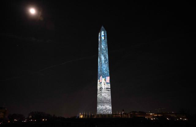 An image of the moon landing is projected onto the Washington Monument during the "Illumination of America" event marking America’s 250th anniversary at the National Mall in Washington, DC, on January 2, 2026, as the January Wolf Supermoon rises in the back. (Photo by ANDREW CABALLERO-REYNOLDS / AFP)