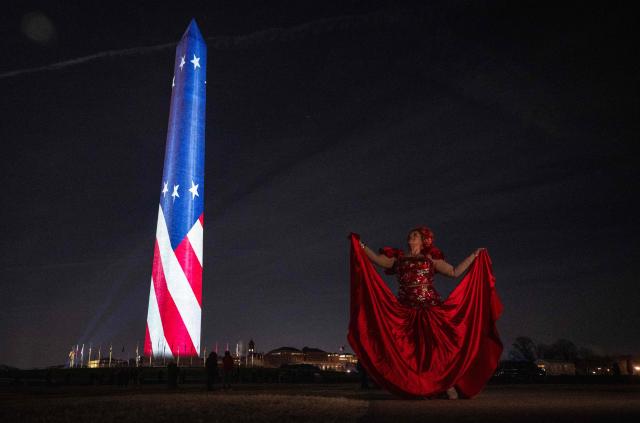 Guajira Solano dances while a friend records her, as stars and stripes are projected onto the Washington Monument during the "Illumination of America" event marking America’s 250th anniversary at the National Mall in Washington, DC, on January 2, 2026. (Photo by ANDREW CABALLERO-REYNOLDS / AFP)