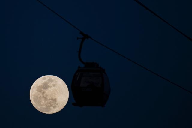 TOPSHOT - The first moon of the year, the "Wolf Moon," is seen rising next to a cable car in the San Agustin neighborhood in eastern Caracas on January 2, 2026. (Photo by Federico PARRA / AFP)