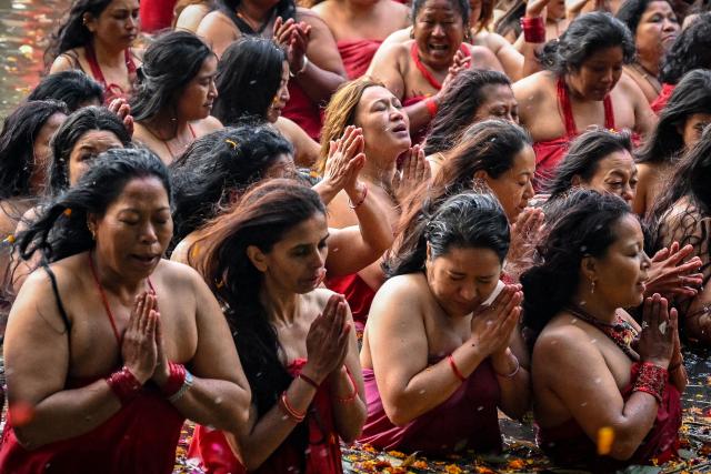 TOPSHOT - Hindu devotees pray while taking a holy dip in the Shali River on the occasion of the Swasthani Brata Katha festival on the outskirts of Kathmandu on January 3, 2026. (Photo by PRAKASH MATHEMA / AFP)