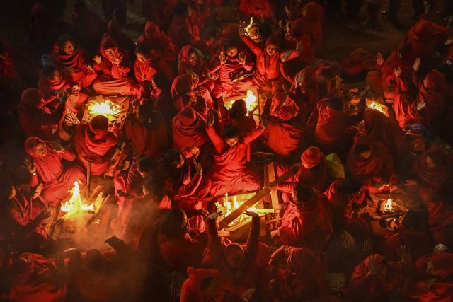 Hindu devotees warm themselves around bonfires before taking a holy dip in the Shali River on the occasion of the Swasthani Brata Katha festival on the outskirts of Kathmandu on January 3, 2026. (Photo by Prakash MATHEMA / AFP)
