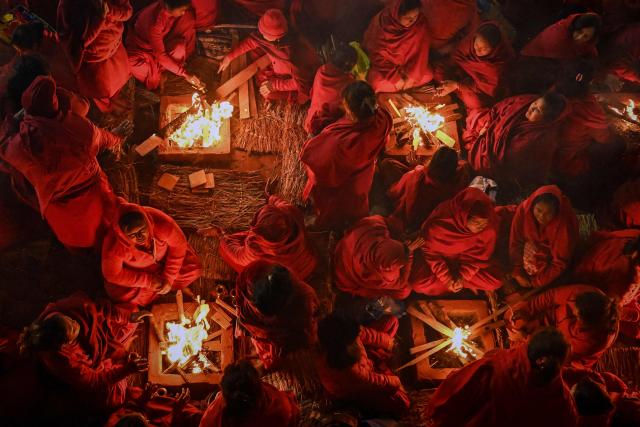 Hindu devotees warm themselves around bonfires before taking a holy dip in the Shali River on the occasion of the Swasthani Brata Katha festival on the outskirts of Kathmandu on January 3, 2026. (Photo by Prakash MATHEMA / AFP)