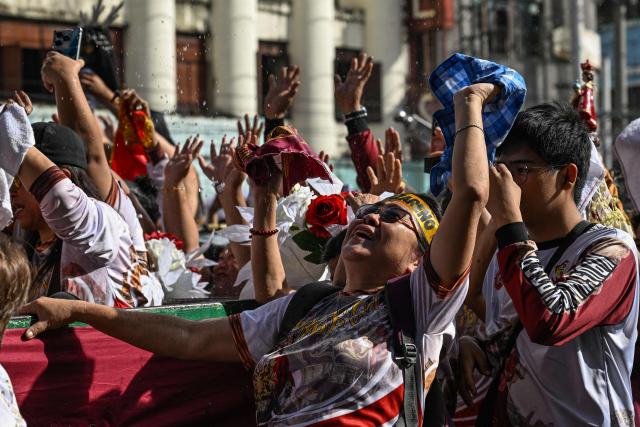 Catholic devotees are showered with holy water during the blessing of Jesus the Nazarene replicas at Quiapo in Manila on January 3, 2026, ahead of the annual "Black Nazarene" procession on January 9 that millions of Catholic devotees are expected to attend. (Photo by Jam STA ROSA / AFP)