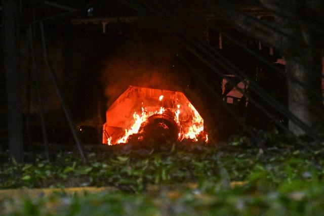 A vehicle burns at La Carlota air base in Caracas after a series of explosions on January 3, 2026. Loud explosions, accompanied by sounds resembling aircraft flyovers, were heard in Caracas around 2:00 am (0600 GMT) on January 3, an AFP journalist reported. The explosions come as US President Donald Trump, who has deployed a navy task force to the Caribbean, raised the possibility of ground strikes against Venezuela. (Photo by Juan BARRETO / AFP)
