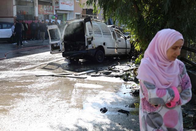 People stand at the site of an Israeli strike that targeted a car in the southern Lebanese village of Khiam on January 3, 2026. Despite a November 2024 ceasefire that was supposed to end more than a year of hostilities between Israel and the Iran-backed Hezbollah group, Israel has kept up strikes on Lebanon and has maintained troops in five areas it deems strategic. (Photo by Rabih DAHER / AFP)