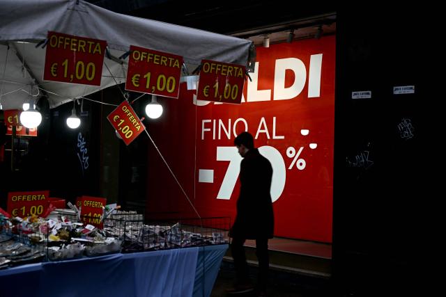 A man walks past a shopping window, advertising a seasonal sales in downtown Rome on January 3, 2026. (Photo by Filippo MONTEFORTE / AFP)