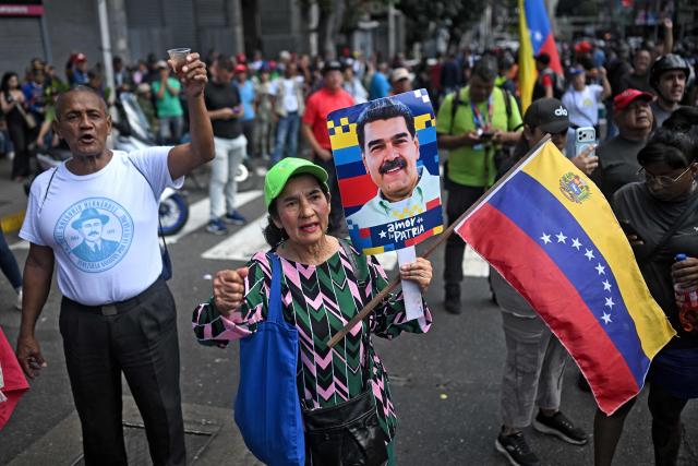 Supporters of Venezuela's President Nicolas Maduro with a national flag and a portrait of him, gather in the streets of Caracas on January 3, 2026, after US forces captured him. President Donald Trump said Saturday that US forces had captured Venezuela's leader Nicolas Maduro after bombing the capital Caracas and other cities in a dramatic climax to a months-long standoff between Trump and his Venezuelan arch-foe. (Photo by Federico PARRA / AFP)