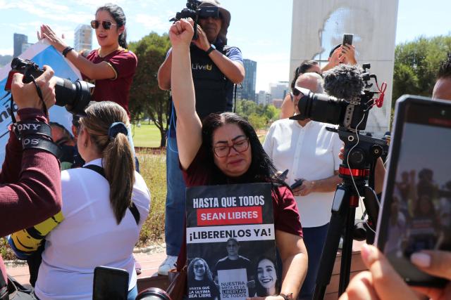 A Venezuelan woman living in Ecuador raises her fist as she holds a sign reading "Until they are all free. Free them now!", referring to people detained in Venezuela, during a gathering in Quito on January 3, 2026, after US forces captured Venezuelan leader Nicolas Maduro. President Donald Trump said Saturday that US forces had captured Venezuela's leader Nicolas Maduro after bombing the capital Caracas and other cities in a dramatic climax to a months-long standoff between Trump and his Venezuelan arch-foe. (Photo by Galo Paguay / AFP)