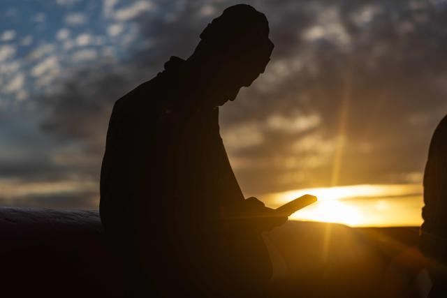 A migrant uses his mobile phone onboard of the rescue ship "Ocean Viking" operated by the NGO SOS Mediterranee, as they sail at sea to the designated port of disembarkation in Savona, northwestern Italy, on January 3, 2026. 33 migrants were rescued by crew members of the migrants rescue ship "Ocean Viking" operated by the NGO SOS Mediterranee. They had been stranded on the oil tanker the 'Maridive 703' since their initial rescue 5 days ago in the joint search zone between Malta and Tunisia in international Mediterranean waters. (Photo by Sameer Al-DOUMY / AFP)