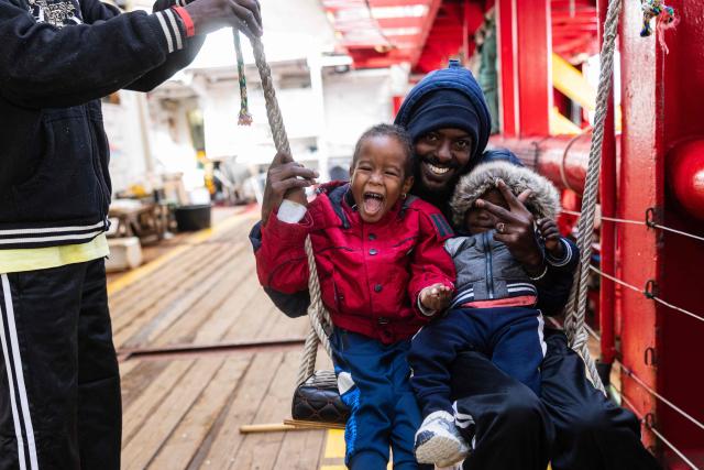 Migrants play on a swing onboard of the rescue ship "Ocean Viking" operated by the NGO SOS Mediterranee, as they sail at sea to the designated port of disembarkation in Savona, northwestern Italy, on January 3, 2026. 33 migrants were rescued by crew members of the migrants rescue ship "Ocean Viking" operated by the NGO SOS Mediterranee. They had been stranded on the oil tanker the 'Maridive 703' since their initial rescue 5 days ago in the joint search zone between Malta and Tunisia in international Mediterranean waters. (Photo by Sameer Al-DOUMY / AFP)