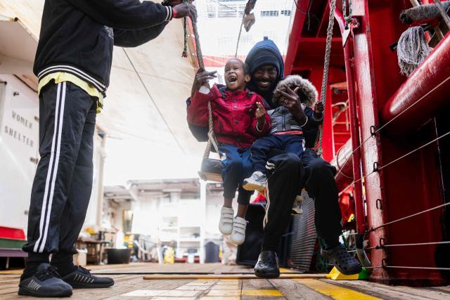 Migrants play on a swing onboard of the rescue ship "Ocean Viking" operated by the NGO SOS Mediterranee, as they sail at sea to the designated port of disembarkation in Savona, northwestern Italy, on January 3, 2026. 33 migrants were rescued by crew members of the migrants rescue ship "Ocean Viking" operated by the NGO SOS Mediterranee. They had been stranded on the oil tanker the 'Maridive 703' since their initial rescue 5 days ago in the joint search zone between Malta and Tunisia in international Mediterranean waters. (Photo by Sameer Al-DOUMY / AFP)