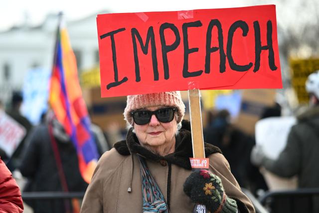 A protester holds a placard during a demonstration against US military action in Venezuela in Lafayette Square in Washington, DC, on January 3, 2026. US President Donald Trump said Saturday that the United States will "run" Venezuela and tap its huge oil reserves after snatching leftist leader Nicolas Maduro out of the country during a bombing raid on Caracas. Trump's announcement came hours after a lightning attack in which special forces grabbed Maduro and his wife, while airstrikes pounded multiple sites, stunning the capital city. (Photo by Mandel NGAN / AFP)