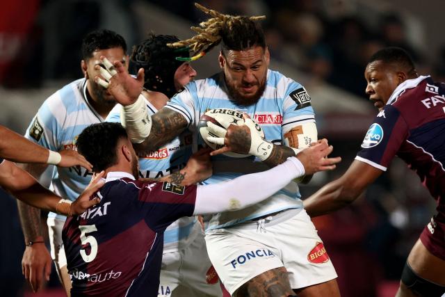 Racing 92' Fijian number 8 Nathan Hughes (C) is tackled by Bordeaux-Begles' French lock Cyril Cazeaux during the French Top14 rugby union match between Union Bordeaux-Begles (UBB) and Racing 92 at the Chaban-Delmas Stadium in Bordeaux, south-western France on January 3, 2026. (Photo by ROMAIN PERROCHEAU / AFP)