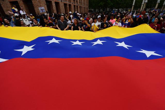 People display a giant Venezuelan flag as they celebrate in Medellín, Colombia, on January 3, 2026, after US forces captured Venezuelan leader Nicolas Maduro. President Donald Trump said Saturday that US forces had captured Venezuela's leader Nicolas Maduro after bombing the capital Caracas and other cities in a dramatic climax to a months-long standoff between Trump and his Venezuelan arch-foe. (Photo by JAIME SALDARRIAGA / AFP)