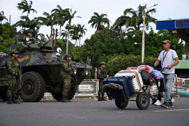 A man walks past military vehicles at the border crossing with Venezuela in Cucuta, Colombia, on January 3, 2026, after US forces captured Venezuela's President Nicolas Maduro. President Donald Trump said on January 3, 2026, that US forces had captured Venezuela's leader Nicolas Maduro after bombing the capital Caracas and other cities in a dramatic climax to a months-long standoff between Trump and his Venezuelan arch-foe. (Photo by Raul ARBOLEDA / AFP)