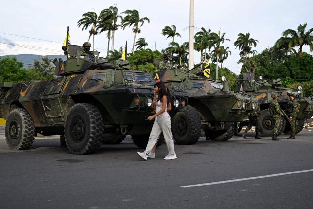 A woman walks past military vehicles at the border crossing with Venezuela in Cucuta, Colombia, on January 3, 2026, after US forces captured Venezuela's President Nicolas Maduro. President Donald Trump said on January 3, 2026, that US forces had captured Venezuela's leader Nicolas Maduro after bombing the capital Caracas and other cities in a dramatic climax to a months-long standoff between Trump and his Venezuelan arch-foe. (Photo by Raul ARBOLEDA / AFP)