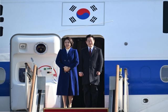 South Korea’s President Lee Jae Myung (R) and his wife Kim Hea Kyung (L) board their plane to depart for China at Seoul Air Base in Seongnam on January 4, 2026. South Korea's President Lee Jae Myung left for China on January 4, eager to boost economic ties with Seoul's largest trading partner while keeping a lid on potentially explosive issues such as Taiwan. (Photo by Jung Yeon-je / AFP)