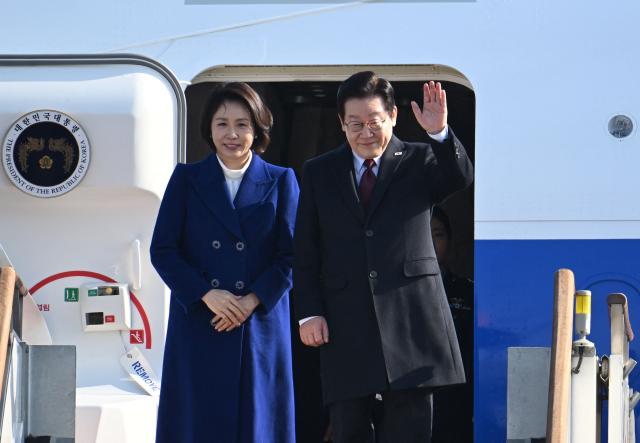 South Korea’s President Lee Jae Myung (R) and his wife Kim Hea Kyung (L) board their plane to depart for China at Seoul Air Base in Seongnam on January 4, 2026. South Korea's President Lee Jae Myung left for China on January 4, eager to boost economic ties with Seoul's largest trading partner while keeping a lid on potentially explosive issues such as Taiwan. (Photo by Jung Yeon-je / AFP)