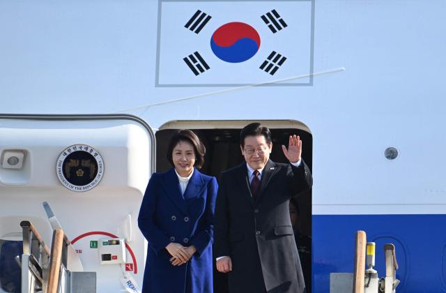 South Korea’s President Lee Jae Myung (R) and his wife Kim Hea Kyung (L) board their plane to depart for China at Seoul Air Base in Seongnam on January 4, 2026. South Korea's President Lee Jae Myung left for China on January 4, eager to boost economic ties with Seoul's largest trading partner while keeping a lid on potentially explosive issues such as Taiwan. (Photo by Jung Yeon-je / AFP)