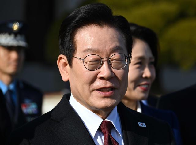South Korea’s President Lee Jae Myung (C) and his wife Kim Hea Kyung (centre R) walk towards their plane to depart for China at Seoul Air Base in Seongnam on January 4, 2026. South Korea's President Lee Jae Myung left for China on January 4, eager to boost economic ties with Seoul's largest trading partner while keeping a lid on potentially explosive issues such as Taiwan. (Photo by Jung Yeon-je / AFP)