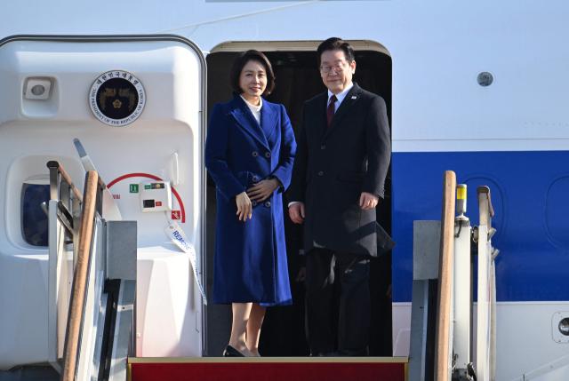 South Korea’s President Lee Jae Myung (R) and his wife Kim Hea Kyung (L) board their plane to depart for China at Seoul Air Base in Seongnam on January 4, 2026. South Korea's President Lee Jae Myung left for China on January 4, eager to boost economic ties with Seoul's largest trading partner while keeping a lid on potentially explosive issues such as Taiwan. (Photo by Jung Yeon-je / AFP)