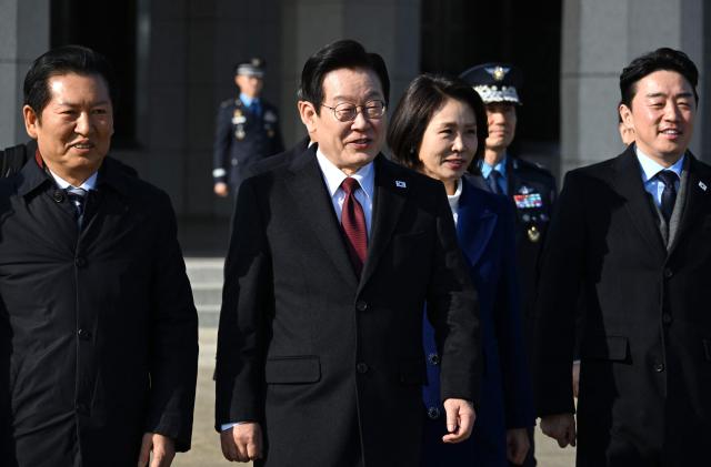 South Korea’s President Lee Jae Myung (C) and his wife Kim Hea Kyung (centre R) walk towards their plane to depart for China at Seoul Air Base in Seongnam on January 4, 2026. South Korea's President Lee Jae Myung left for China on January 4, eager to boost economic ties with Seoul's largest trading partner while keeping a lid on potentially explosive issues such as Taiwan. (Photo by Jung Yeon-je / AFP)