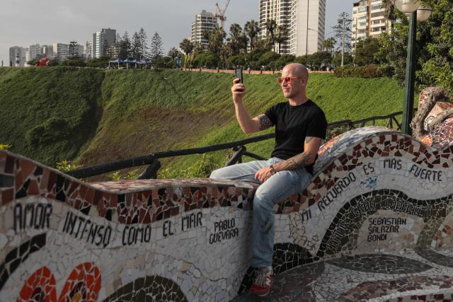A tourist takes pictures with his phone at the Love Park in Miraflores, Lima, on January 3, 2026. (Photo by Connie FRANCE / AFP)