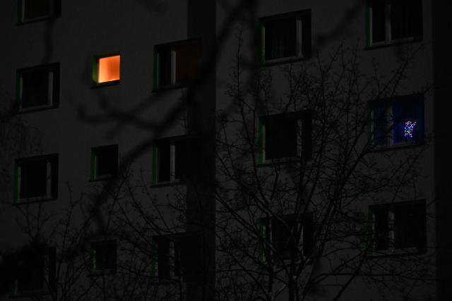 Light is seen through the window of an apartment of a residential building in the Zehlendorf district in southwest Berlin on early January 4, 2026, after power cables in the area were seriously damaged causing a power outage which left tens of thousands of households in the German capital without electricity. The widespread power outage in southwest Berlin, affecting tens of thousands of households, was deliberately caused with incendiary devices, according to Berlin's Senator for Economic Affairs. It was "clearly" a "deliberate act," Senator Giffey said on January 4. The bridge over the Teltow Canal, where five high-voltage and ten medium-voltage cables were destroyed, had been "rigged with incendiary devices." (Photo by RALF HIRSCHBERGER / AFP)