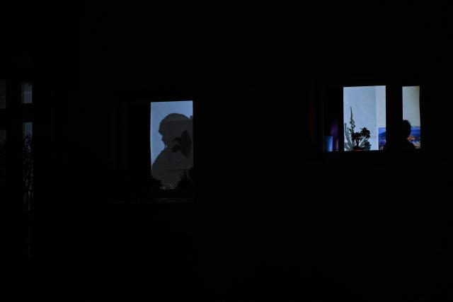 The shadows of residents are seen through windows of an apartment of a residential building in the Zehlendorf district in southwest Berlin on early January 4, 2026, after power cables in the area were seriously damaged causing a power outage which left tens of thousands of households in the German capital without electricity. The widespread power outage in southwest Berlin, affecting tens of thousands of households, was deliberately caused with incendiary devices, according to Berlin's Senator for Economic Affairs. It was "clearly" a "deliberate act," Senator Giffey said on January 4. The bridge over the Teltow Canal, where five high-voltage and ten medium-voltage cables were destroyed, had been "rigged with incendiary devices." (Photo by RALF HIRSCHBERGER / AFP)
