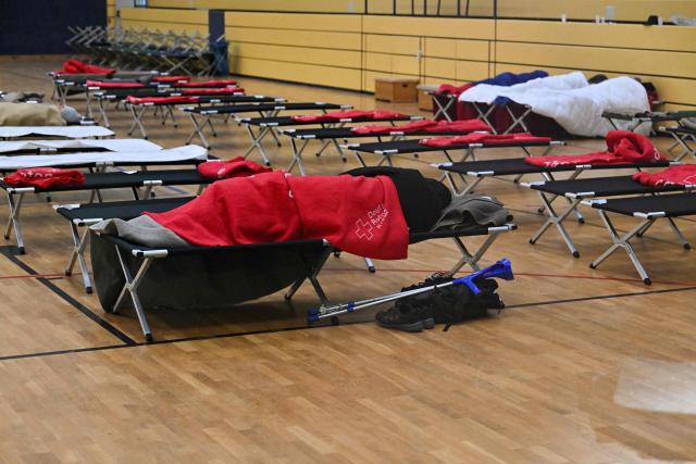 People sleep at a heated emergency shelter of the German Red Cross (Deutsches Rotes Kreuz) set up at the Cole Sports Center in southwest Berlin on early January 4, 2026, after power cables in the area were seriously damaged causing a power outage which left tens of thousands of households in the German capital without electricity. The widespread power outage in southwest Berlin, affecting tens of thousands of households, was deliberately caused with incendiary devices, according to Berlin's Senator for Economic Affairs. It was "clearly" a "deliberate act," Senator Giffey said on January 4. The bridge over the Teltow Canal, where five high-voltage and ten medium-voltage cables were destroyed, had been "rigged with incendiary devices." (Photo by RALF HIRSCHBERGER / AFP)