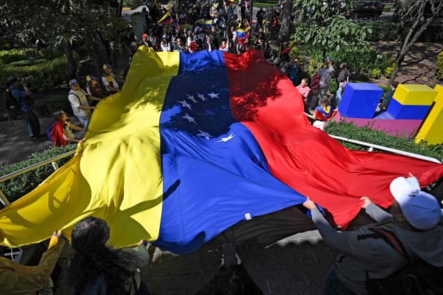 Venezuelans living in Mexico gather to celebrate with a giant national flag at the Lincoln Park in the Polanco neighborgood, in Mexico City, on January 4, 2026, a day after Venezuela's leader Nicolas Maduro was captured in a US strike. Venezuela's military on Sunday recognized Delcy Rodriguez, deputy to ousted president Nicolas Maduro, as the country's acting leader, after US forces extracted the former head of state to face trial. (Photo by Alfredo ESTRELLA / AFP)