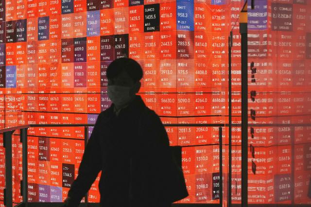 A man walks past an electronic quotation board displaying the Nikkei 225 stock prices on the Tokyo Stock Exchange in Tokyo on January 5, 2026. (Photo by Kazuhiro NOGI / AFP)
