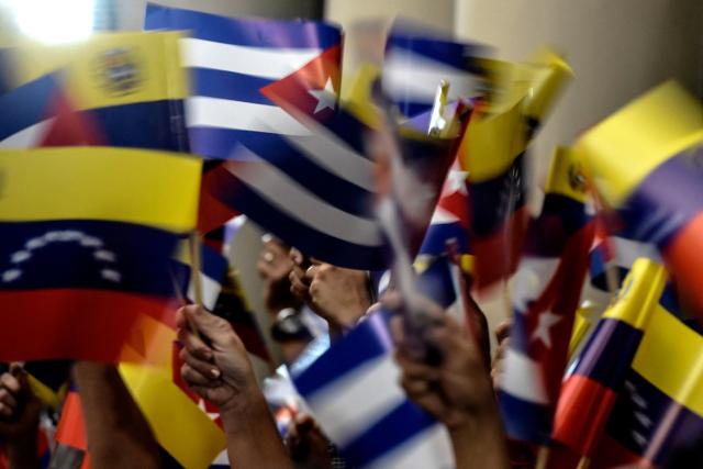 (FILES) Supporters of Venezuelan President Nicolas Maduro wave Venezuelan and Cuban national flags during a ceremony honouring Cuban leader Fidel Castro one day after his death, in Caracas, on November 26, 2016. A total of 32 Cuban nationals were killed during the US attack on Caracas that culminated in the capture of Venezuela's president Nicolas Maduro, the government in Havana said on January 4, 2026. (Photo by JUAN BARRETO / AFP)