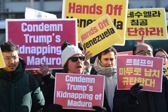 Protesters hold placards during a demonstration condemning the US attack on Venezuela and the seizure of Venezuelan leader Nicolas Maduro, in front of the US embassy in Seoul on January 5, 2026. (Photo by Jung Yeon-je / AFP)