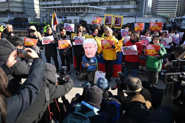 A protester wearing a mask of US President Donald Trump performs during a demonstration condemning the US attack on Venezuela and the seizure of Venezuelan leader Nicolas Maduro, in front of the US embassy in Seoul on January 5, 2026. (Photo by Jung Yeon-je / AFP)
