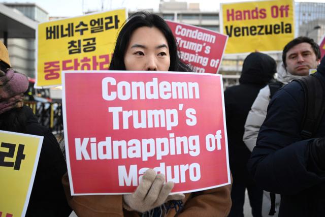 Protesters hold placards during a demonstration condemning the US attack on Venezuela and the seizure of Venezuelan leader Nicolas Maduro, in front of the US embassy in Seoul on January 5, 2026. (Photo by Jung Yeon-je / AFP)